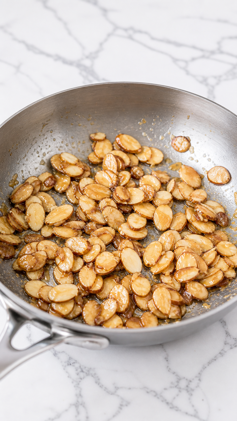 Sliced almonds caramelized with sugar in a small pan