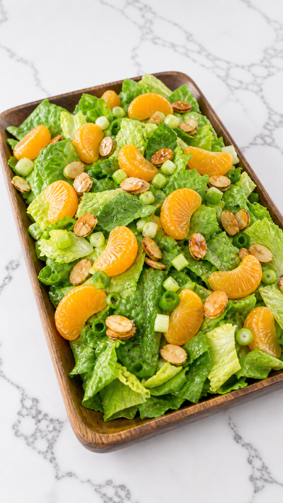 Romaine salad assembled with mandarin oranges, celery, green onions, and candied almonds