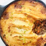 Cast iron skillet shepherd's pie with portion removed to show meat mixture