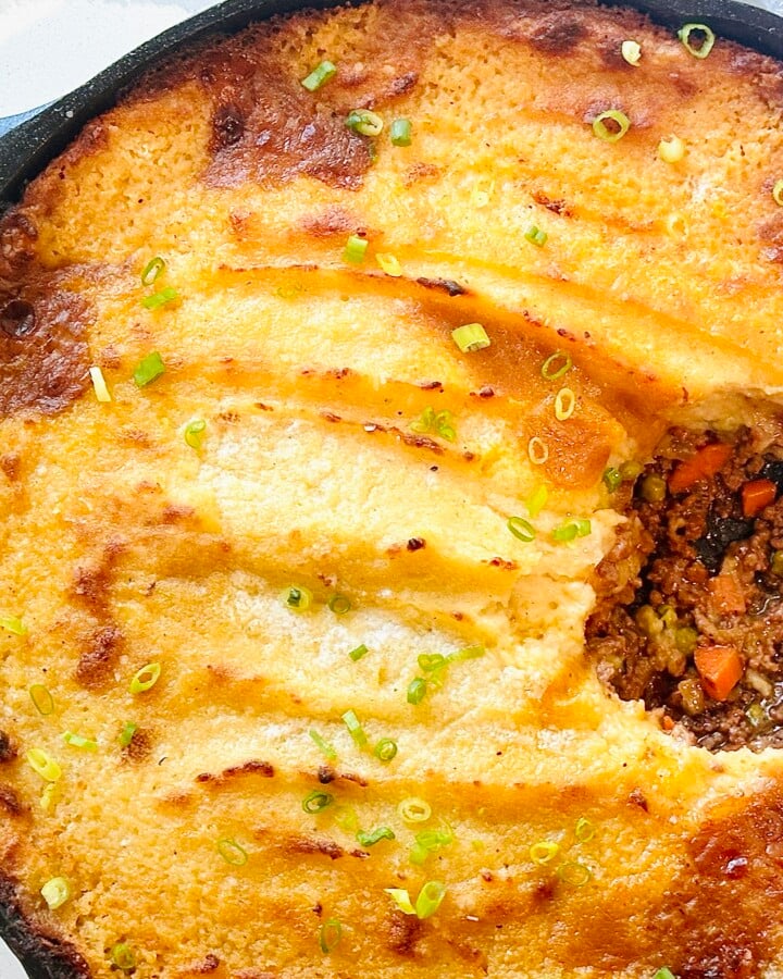 Cast iron skillet shepherd’s pie with portion removed to show meat mixture