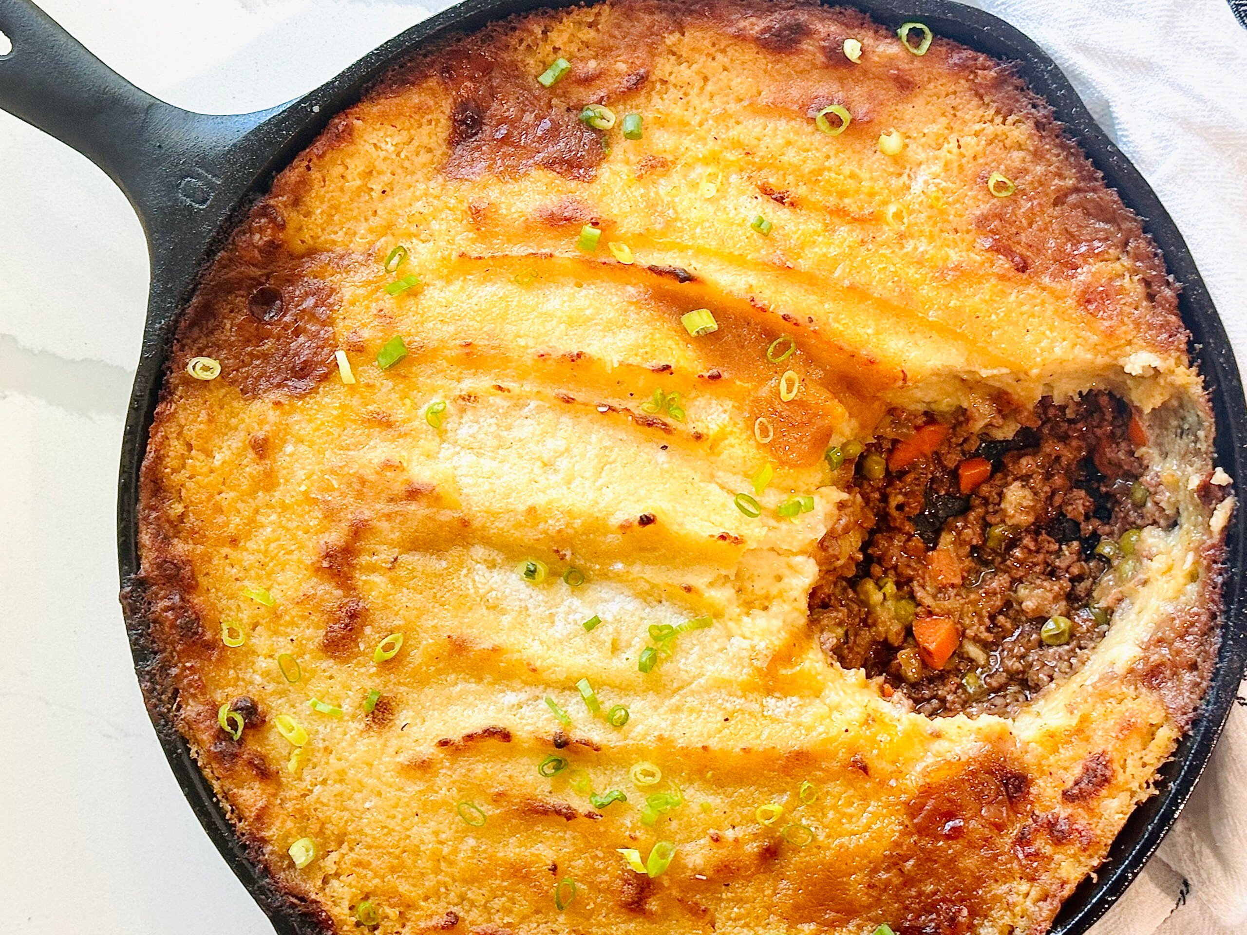 Cast iron skillet shepherd’s pie with portion removed to show meat mixture