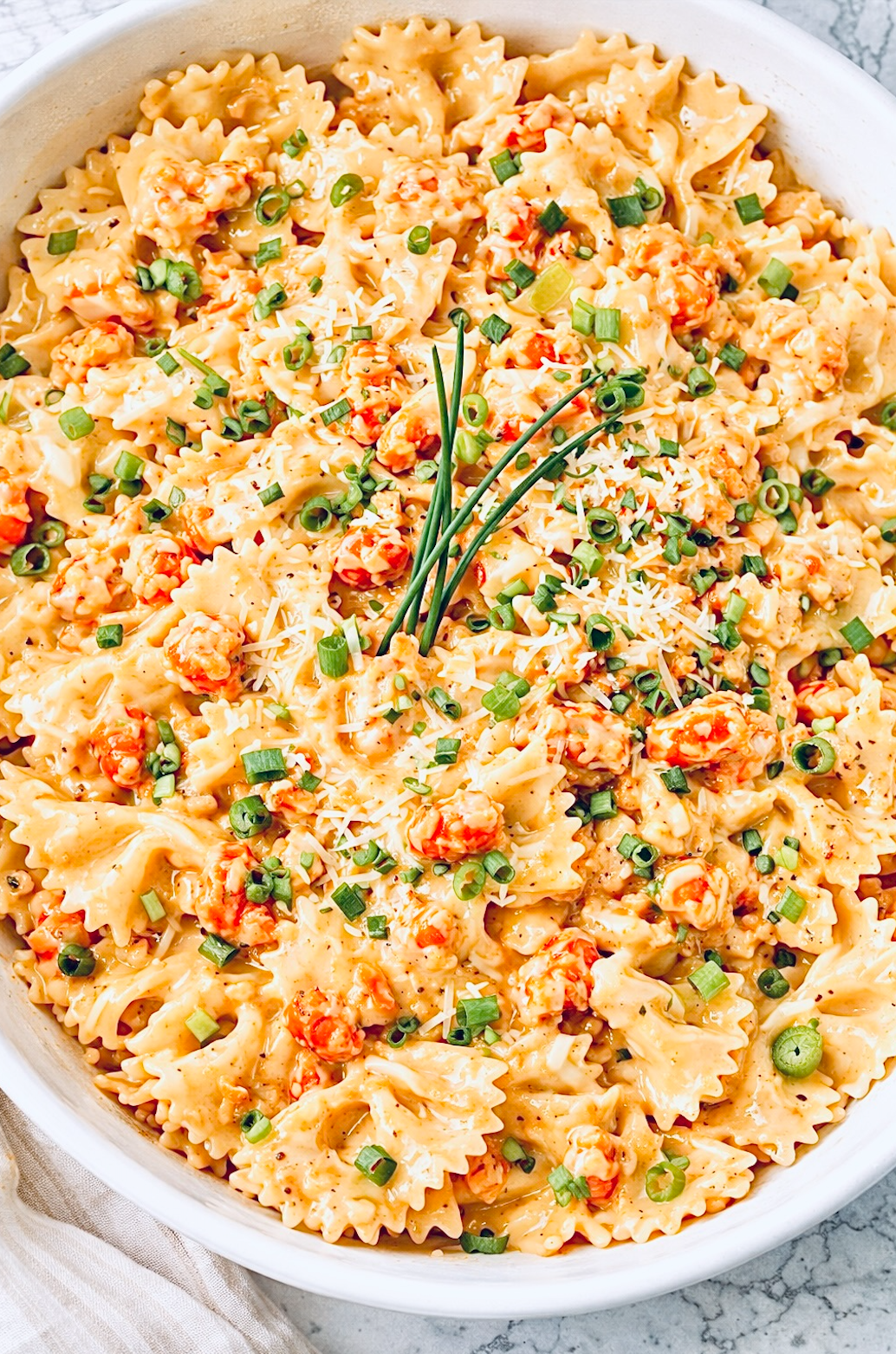 Overhead view of creamy crawfish pasta made with bow tie pasta, Louisiana crawfish tails, green onions, and a rich cream sauce.