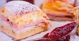 Monte Cristo Sliders dusted in powdered sugar with raspberry jam on the side.