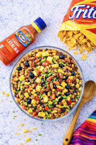Overhead view of Catalina taco salad with ground beef, Fritos, kidney beans, black olives, corn, tomatoes, and shredded lettuce in a large glass serving bowl