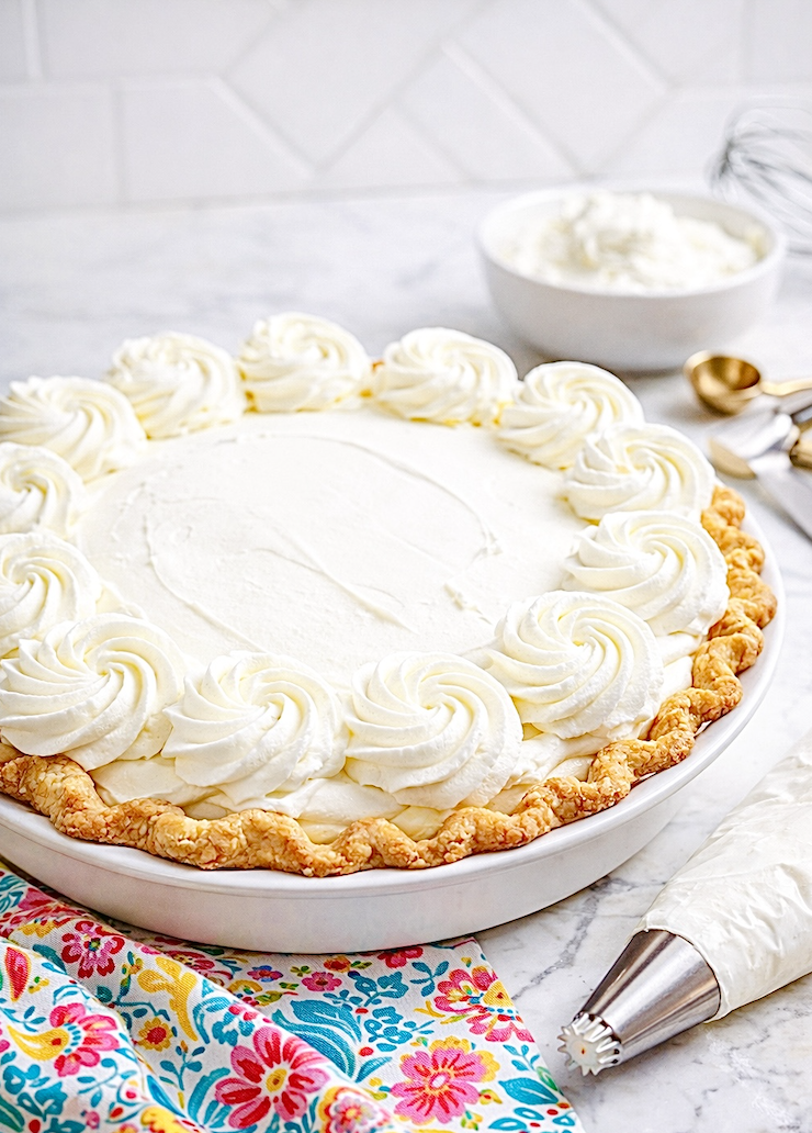 Fully decorated cream pie topped with stabilized whipped cream rosettes around the edge, showing bakery-style whipped cream that stays firm.
