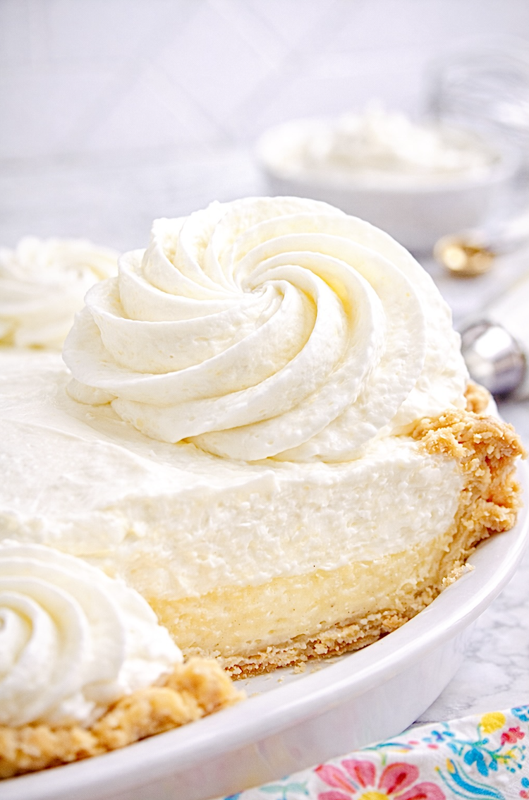 Close-up slice of cream pie topped with stabilized whipped cream swirl, showing thick and fluffy whipped cream texture.