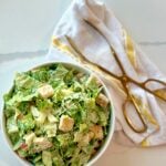 Classic homemade Caesar salad in a white bowl with crisp romaine, creamy dressing, Parmesan, and croutons.