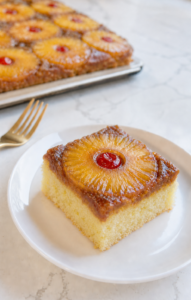 Moist fluffy slice of Pineapple Upside-Down Sheet Cake with caramelized pineapple and cherry.
