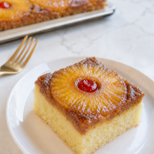Moist fluffy slice of Pineapple Upside-Down Sheet Cake with caramelized pineapple and cherry.