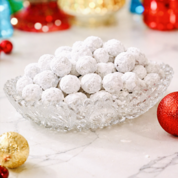 Closeup of Powdered Sugar Cranberries in a cut glass dish with Christmas decorations around it.