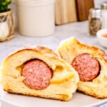 Texas sausage kolache cut in half showing smoky breakfast sausage wrapped in soft sweet yeast dough on a white plate
