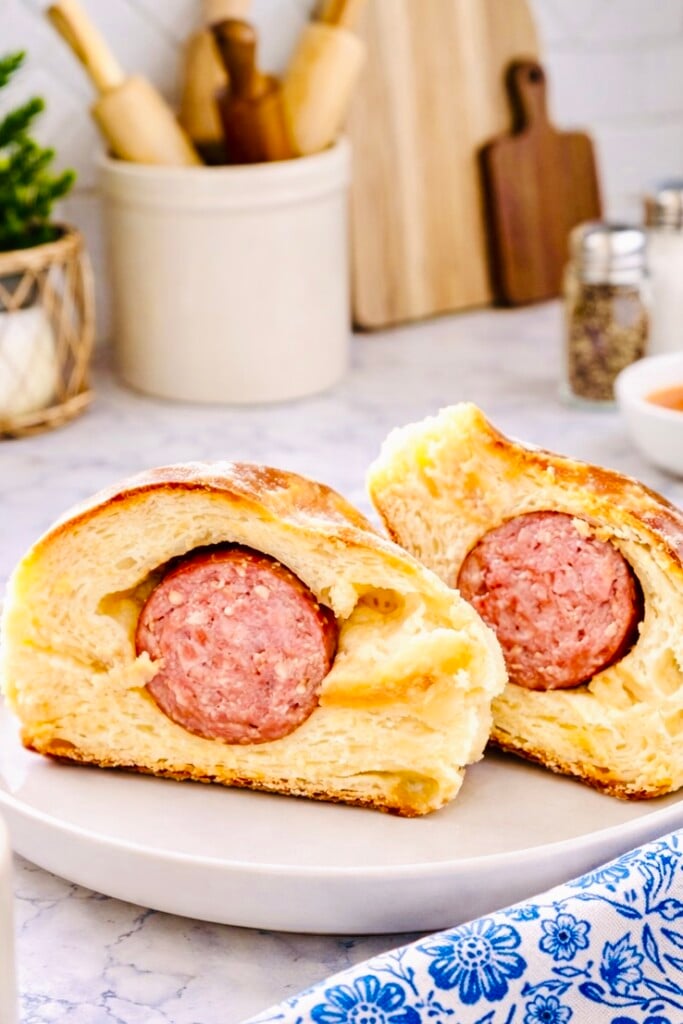 Texas sausage kolache cut in half showing smoky breakfast sausage wrapped in soft sweet yeast dough on a white plate