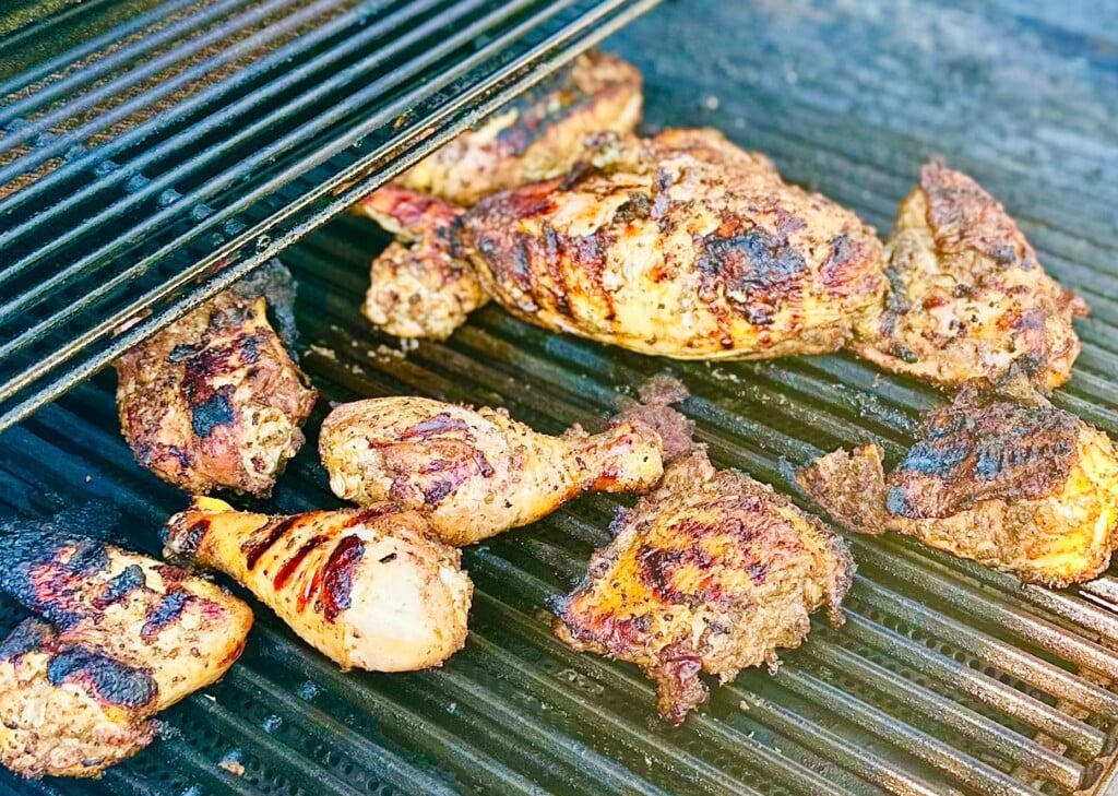 Grilled Caribbean jerk chicken on a charcoal grill with smoky char marks

