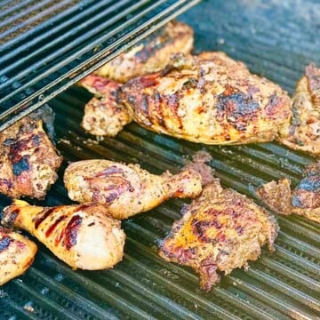 Grilled Caribbean jerk chicken on a charcoal grill with smoky char marks