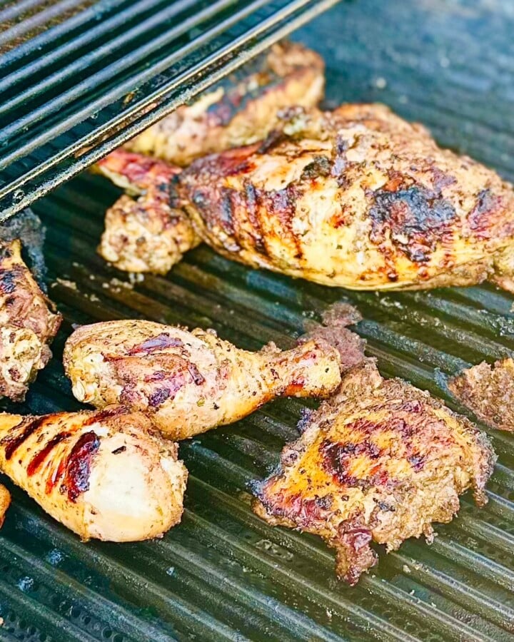 Grilled Caribbean jerk chicken on a charcoal grill with smoky char marks