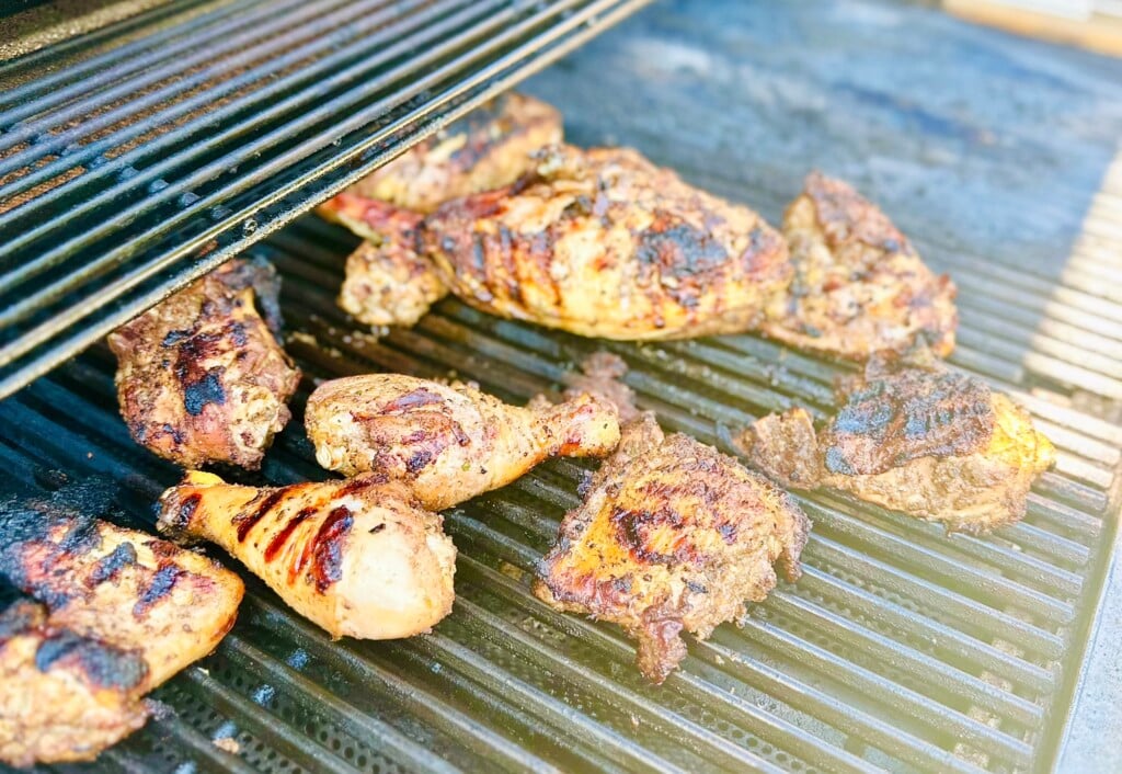 Smoke rising from Grilled Caribbean jerk chicken on a charcoal grill
