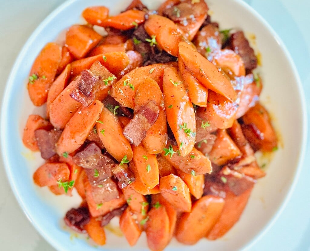 Tender honey-glazed carrots with bacon and thyme served in a white ceramic bowl—perfect holiday side dish.