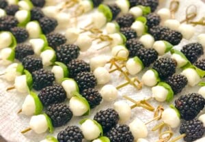 Close-up of blackberry caprese skewers with fresh basil, mozzarella balls, and juicy blackberries drizzled with balsamic glaze.