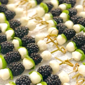 Close-up of blackberry caprese skewers with fresh basil, mozzarella balls, and juicy blackberries drizzled with balsamic glaze.