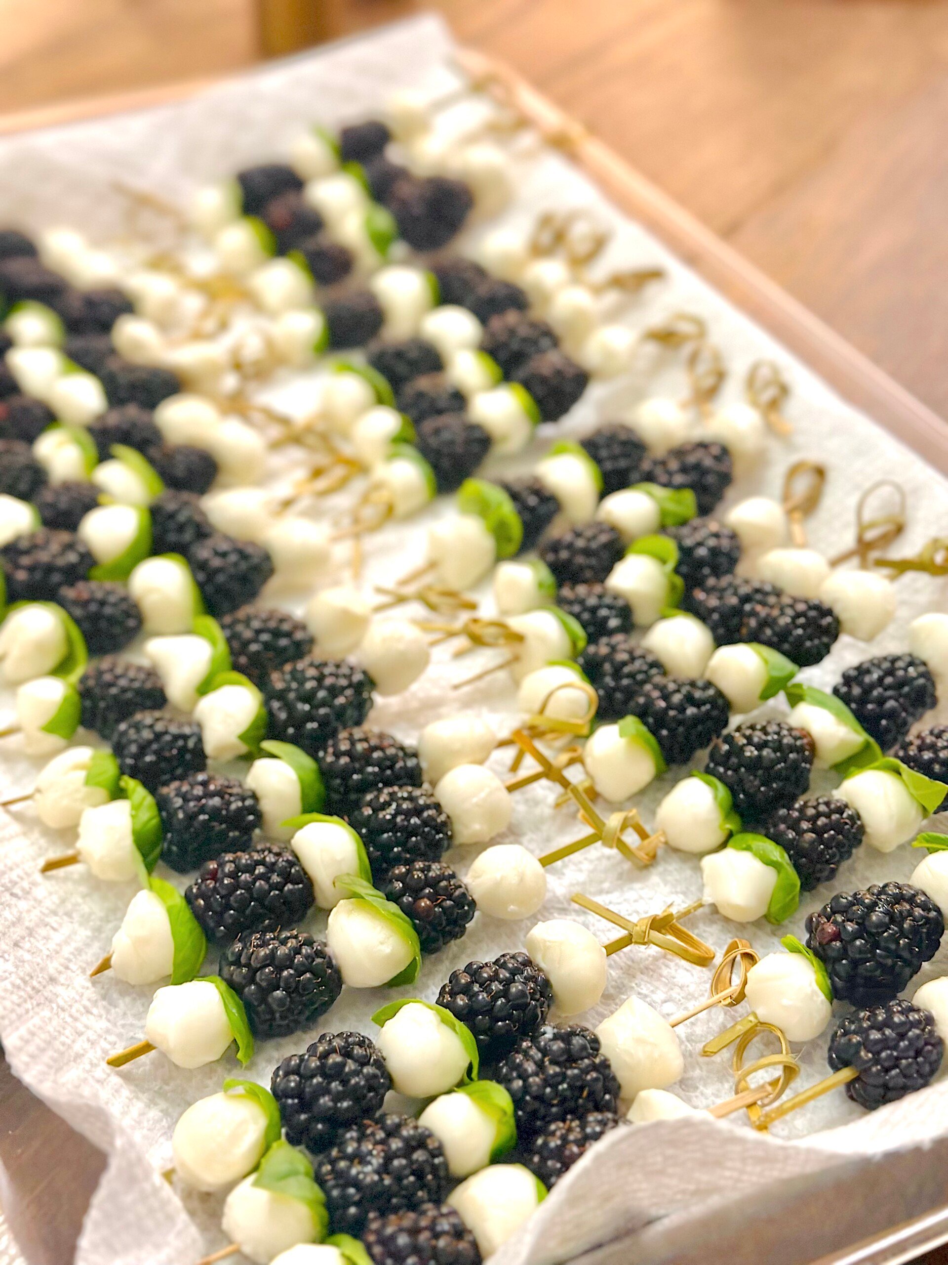 Vibrant skewers featuring ripe blackberries, creamy mozzarella, and basil leaves, arranged in a colorful appetizer display.