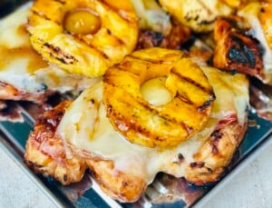 Close-up of grilled chicken layered with prosciutto, Gruyère cheese, and pineapple ring