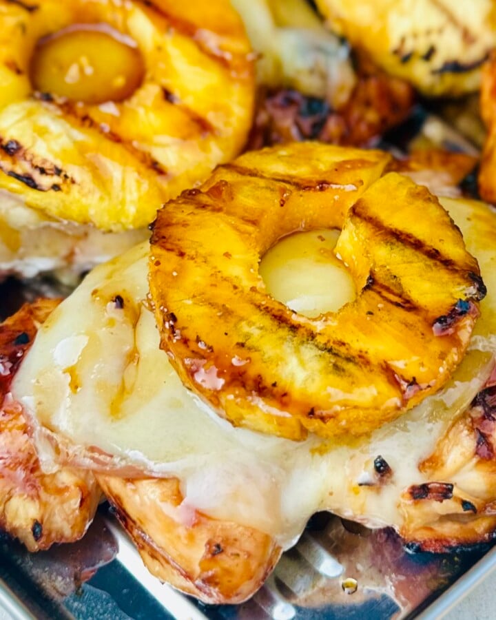 Close-up of grilled chicken layered with prosciutto, Gruyère cheese, and pineapple ring