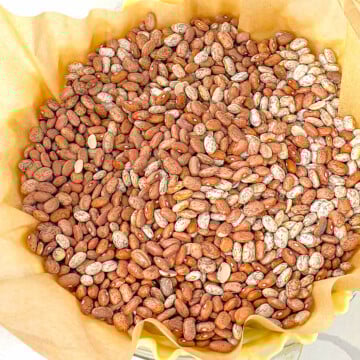 A pie crust lined with parchment paper and filled with dried beans to be blind baked.