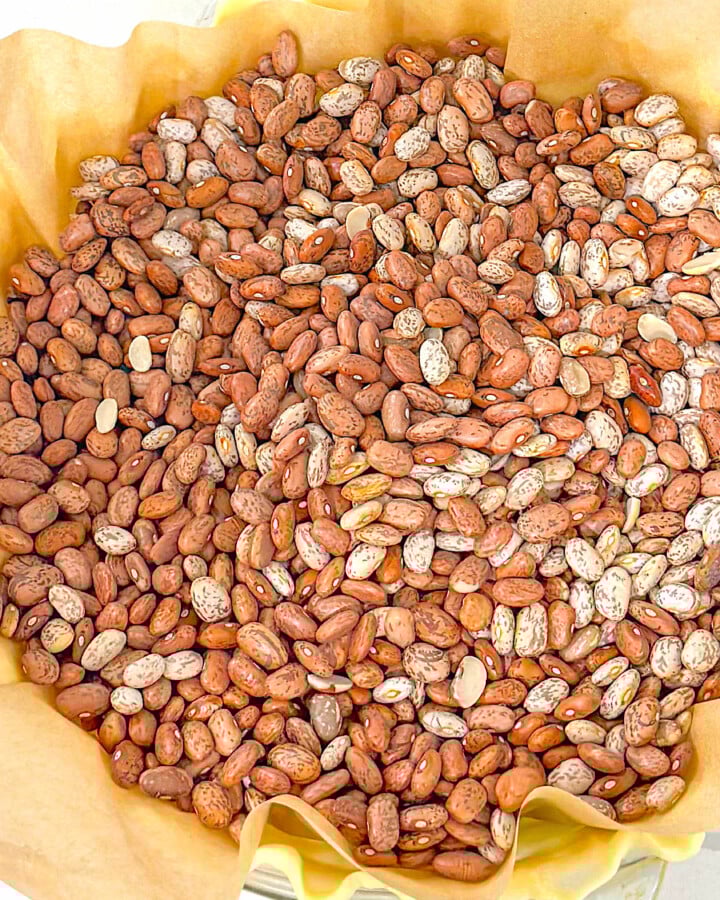 A pie crust lined with parchment paper and filled with dried beans to be blind baked.