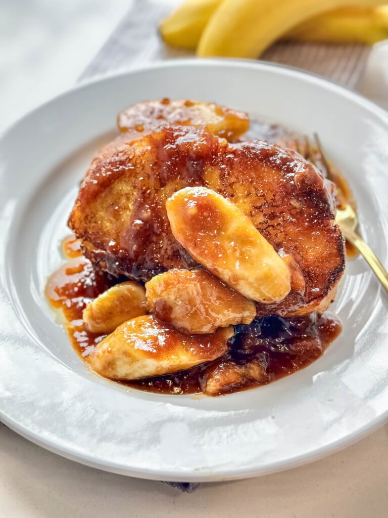 Decadent French toast with banana topping and drizzle of maple syrup.