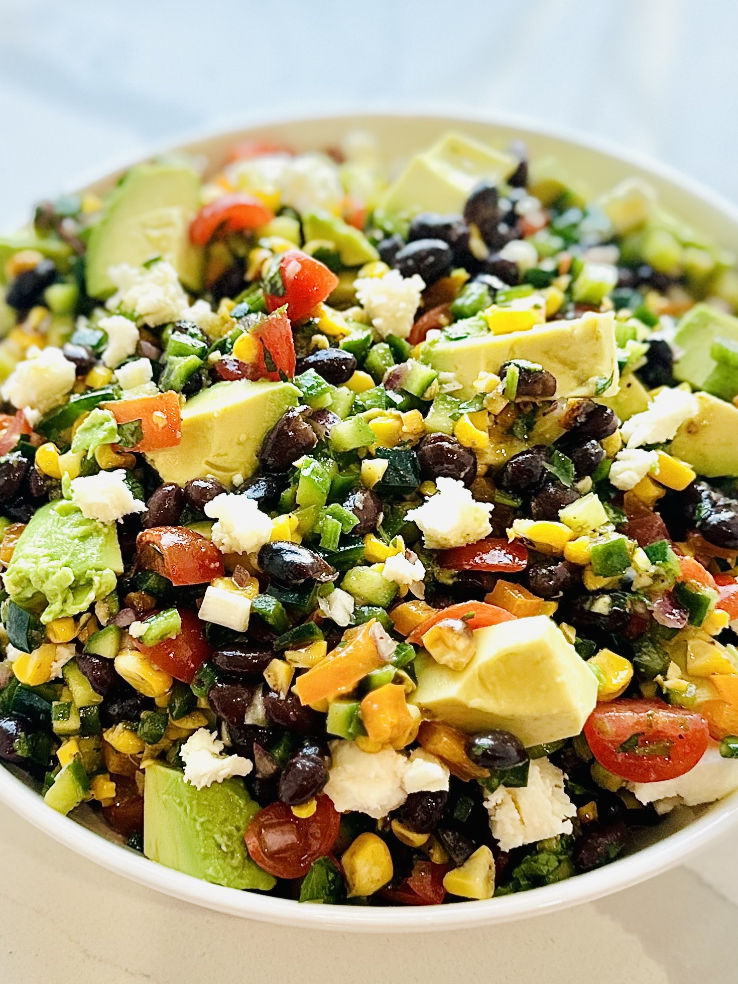Honey lime vinaigrette drizzled over a large bowl of Mexican chopped salad with cilantro and jalapeño