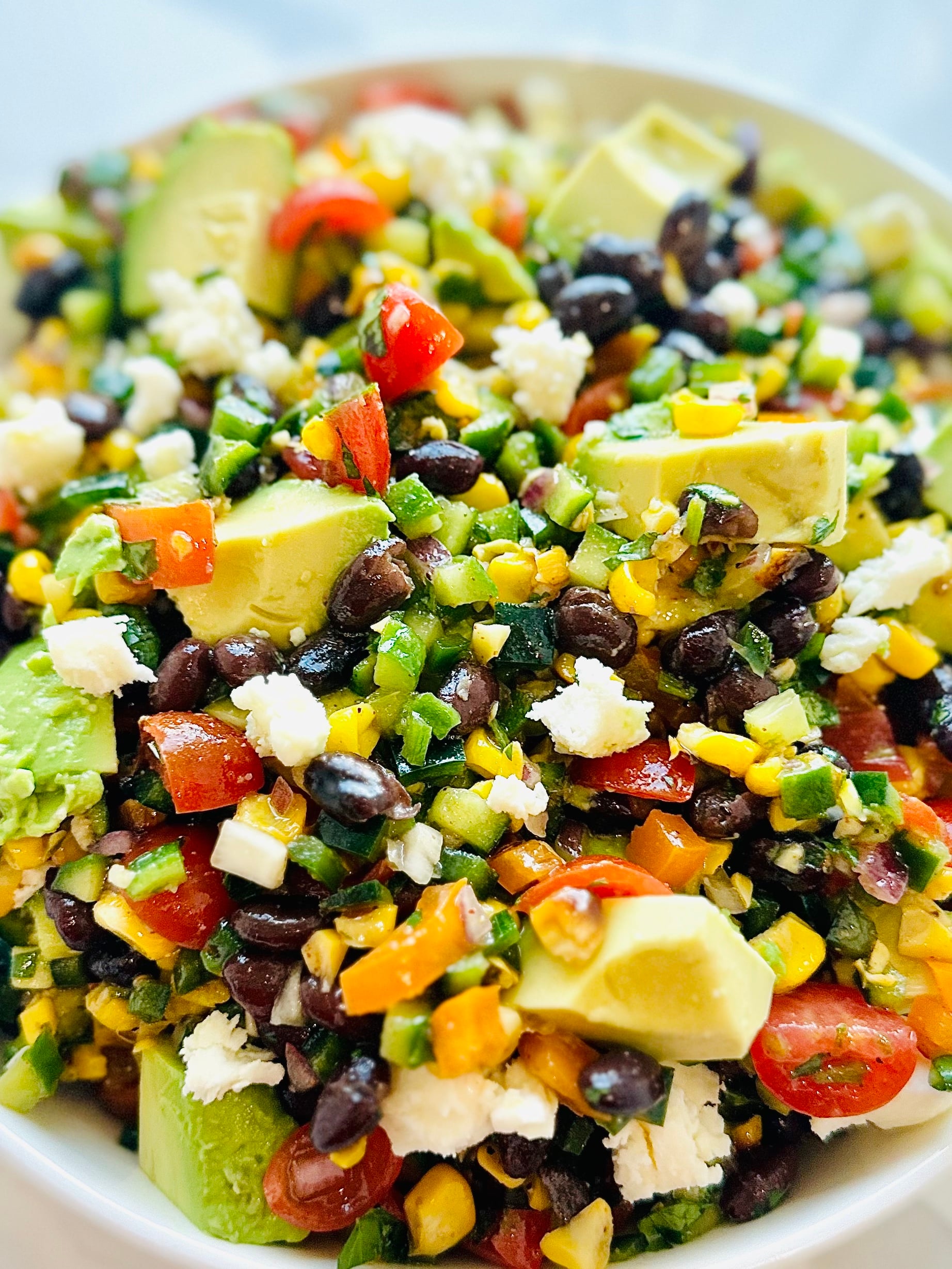 Large white bowl filled with fresh Mexican chopped salad topped with crumbled queso fresco and tortilla strips