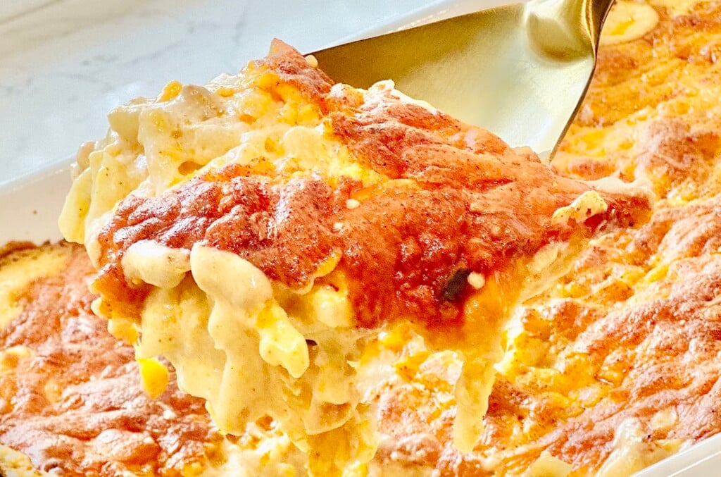Serving a creamy scoop of cheesy hashbrown casserole - warm, golden, and loaded with melted cheddar and tender shredded potatoes.