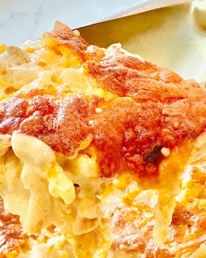 Serving a creamy scoop of cheesy hashbrown casserole - warm, golden, and loaded with melted cheddar and tender shredded potatoes.