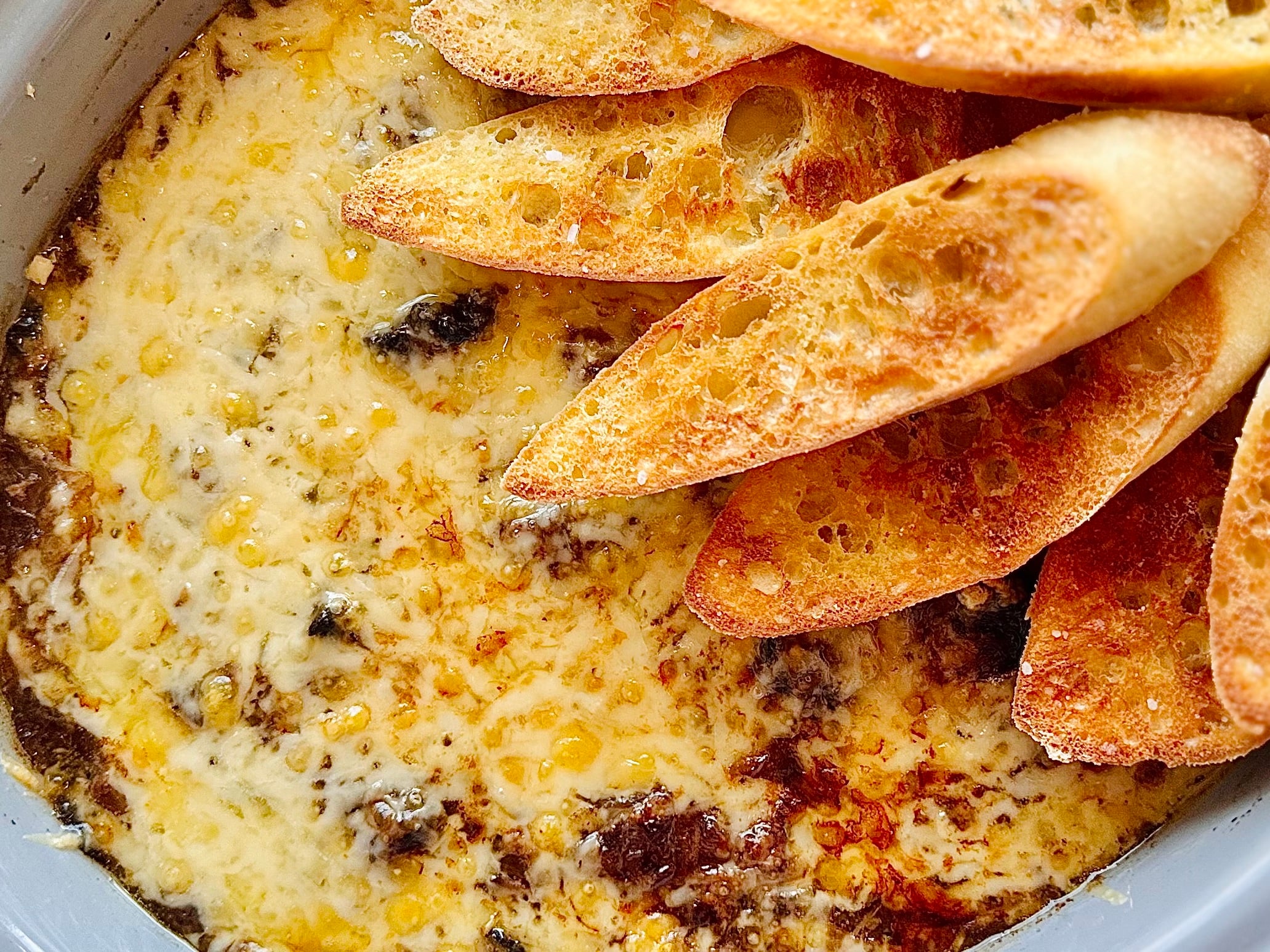 Slow-braised French onion pot roast in a Dutch oven topped with melted Gruyère and served with toasted baguette slices.