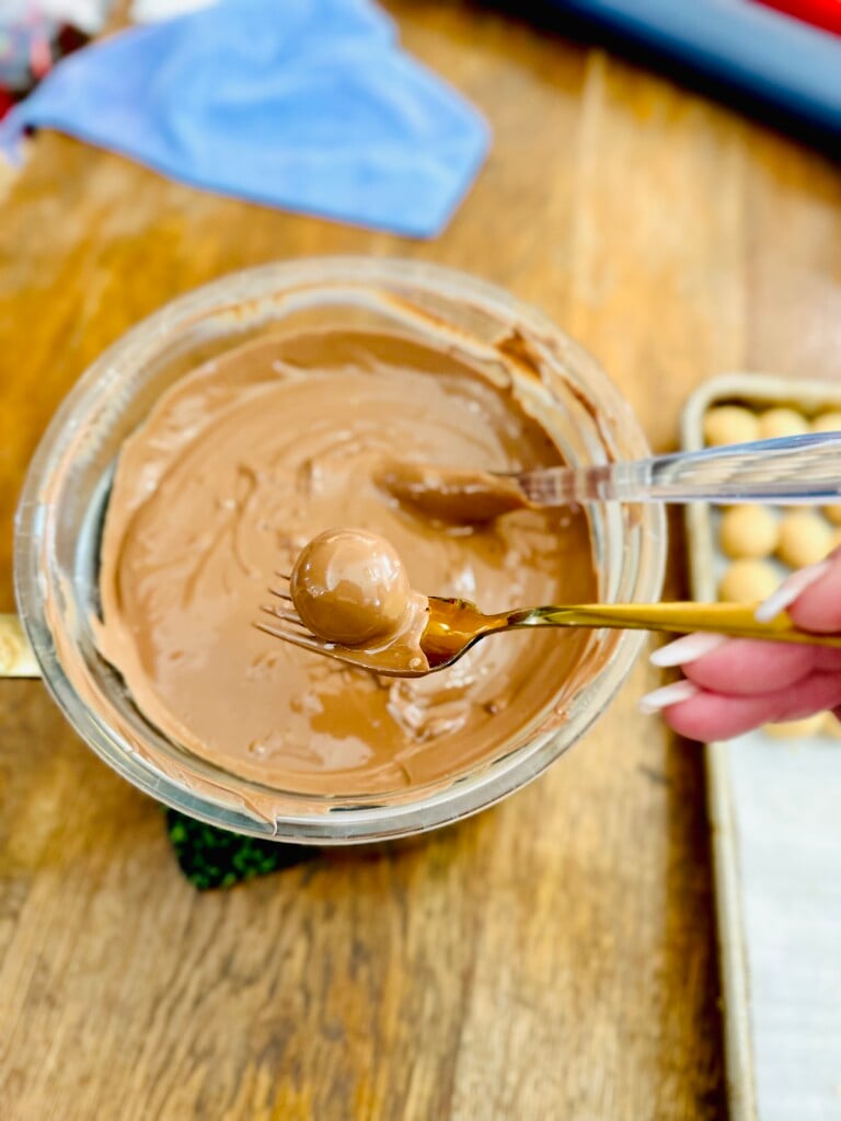 Lifting the peanut butter ball out of the melted chocolate.