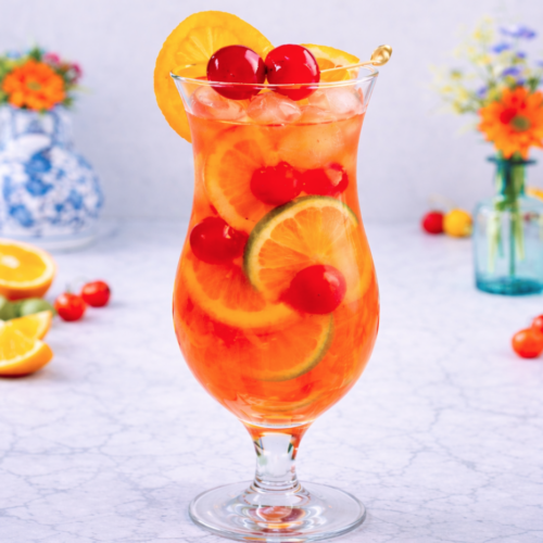 Single hurricane cocktail in a clear hurricane glass with ice, citrus slices, and maraschino cherries, photographed in bright natural light on a marble surface.