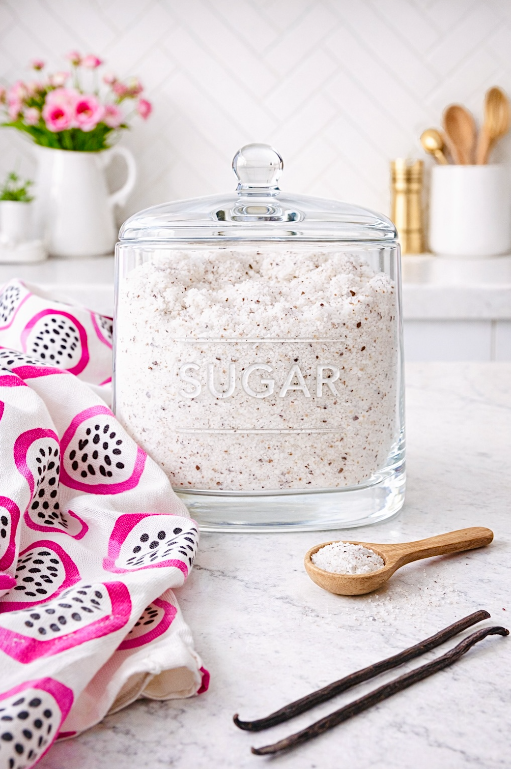 Homemade vanilla sugar in glass storage jar on kitchen counter with vanilla beans and spoon