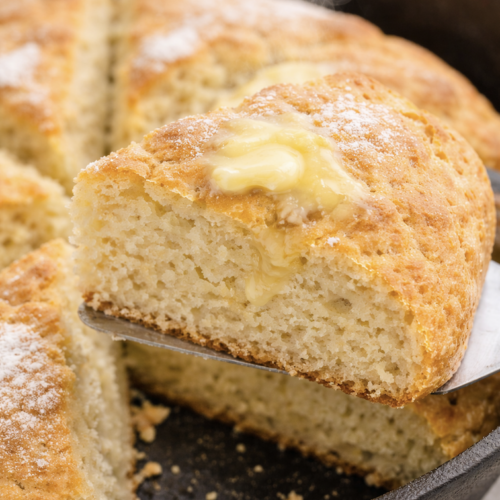 Irish soda bread slice with melted butter on spatula in skillet