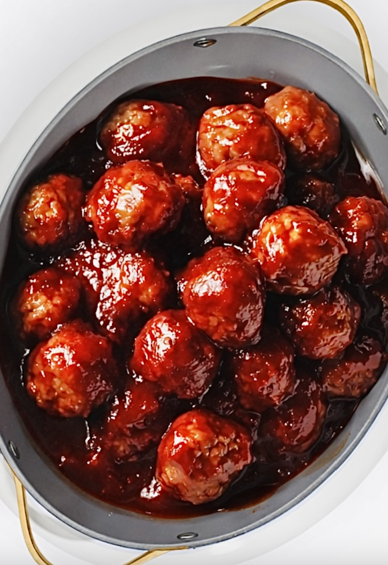 Overhead view of crockpot grape jelly meatballs in rich red sauce in white skillet
