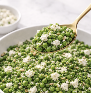 Cropped Spoonful of spring pea salad with feta, mint, chives, and sunflower seeds lifted above a white serving bowl