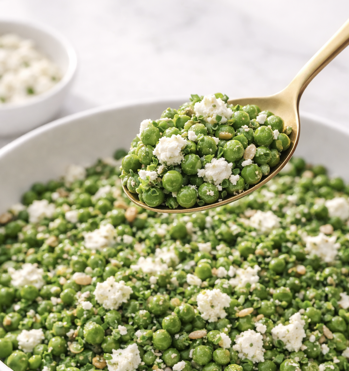 Cropped Spoonful of spring pea salad with feta, mint, chives, and sunflower seeds lifted above a white serving bowl