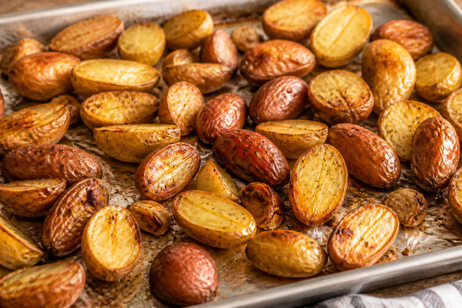 Roasted fingerling potatoes browned on a foil-lined sheet pan after baking