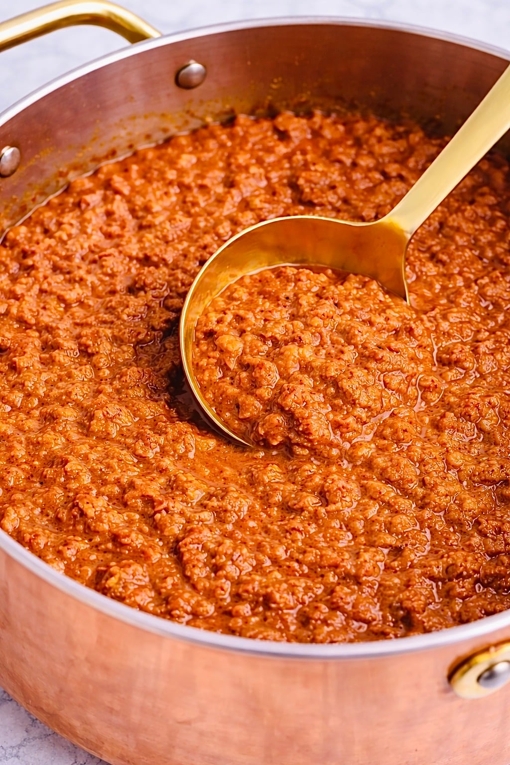 Fine textured Coney Island hot dog chili sauce in a copper pan with a gold ladle