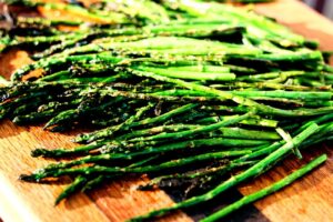 Easy grilled asparagus with garlic, olive oil, and light char marks on a wooden board.