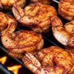 BBQ grilled shrimp skewers cooking on an outdoor grill until opaque pink and lightly charred.