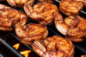 BBQ grilled shrimp skewers cooking on an outdoor grill until opaque pink and lightly charred.