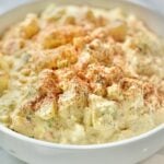 Bowl of Southern potato salad with Duke's mayonnaise dressing, eggs, dill pickles, celery, onion, fresh dill, and paprika.