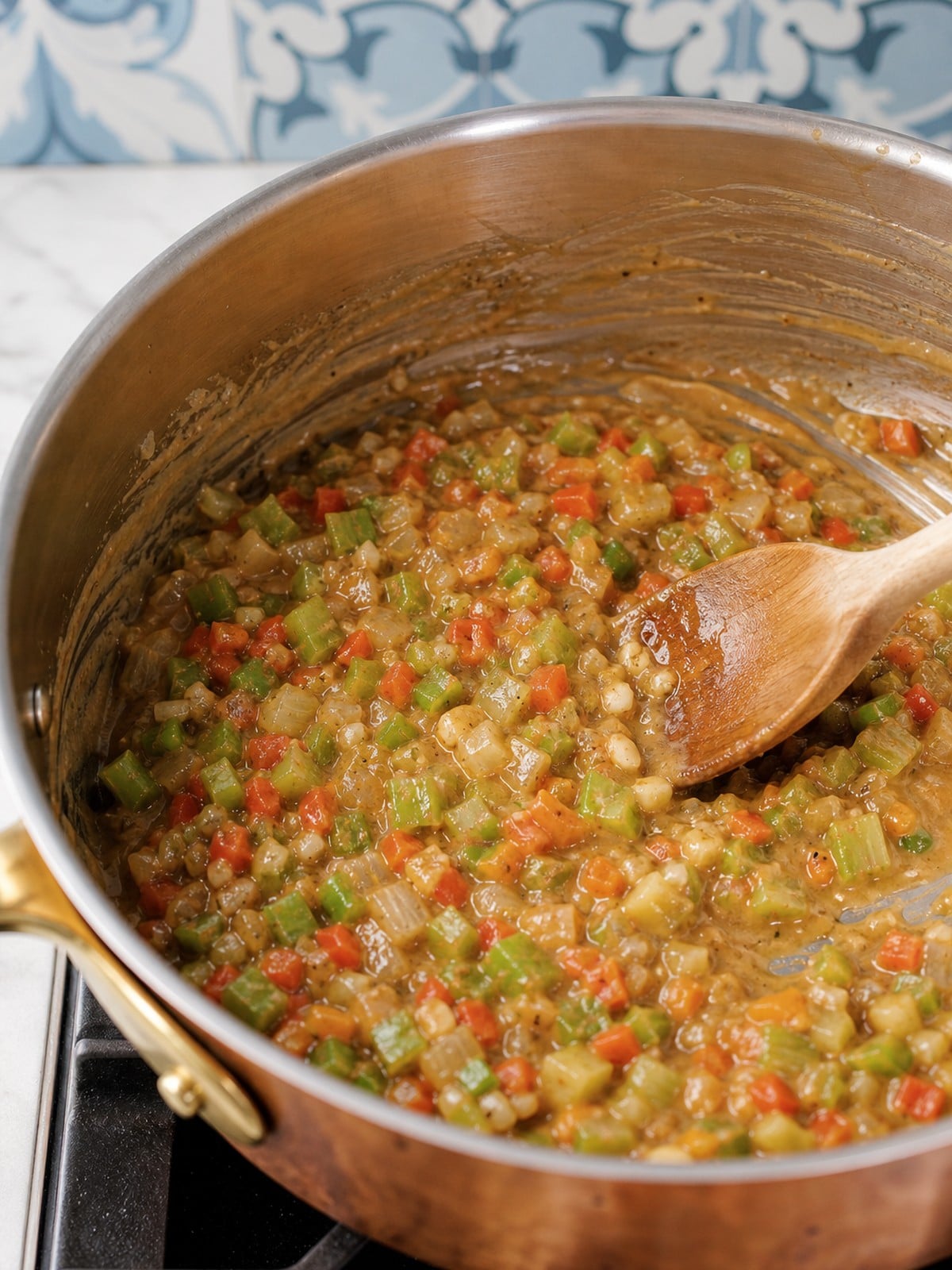 Celery onion and bell pepper stirred into roux for crawfish etouffee.