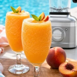 Frozen peach Bellini cocktail with fresh peach garnish by the pool.