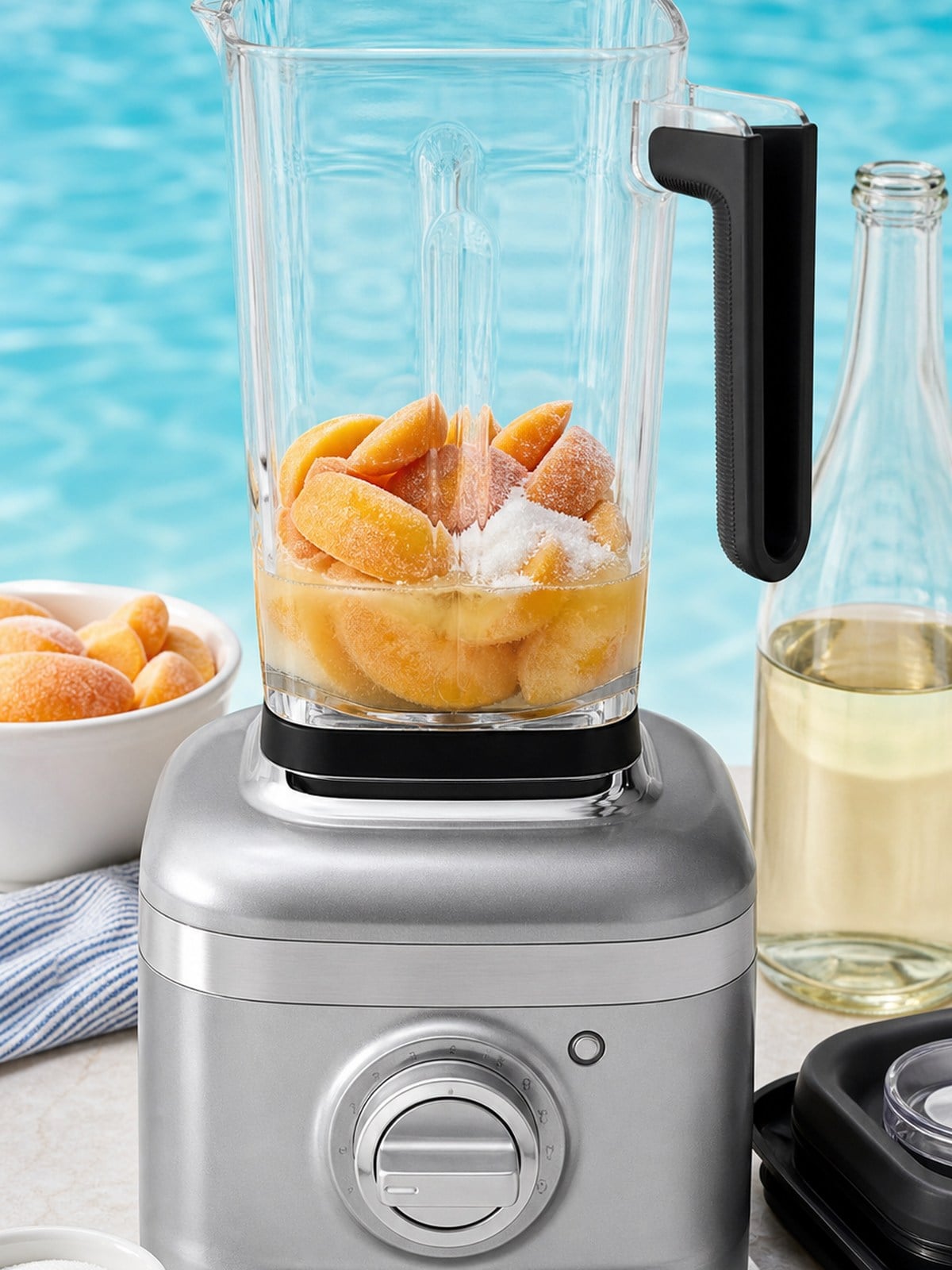 Frozen peaches, sugar, peach schnapps, and sparkling wine loaded into a silver KitchenAid K400-style blender.